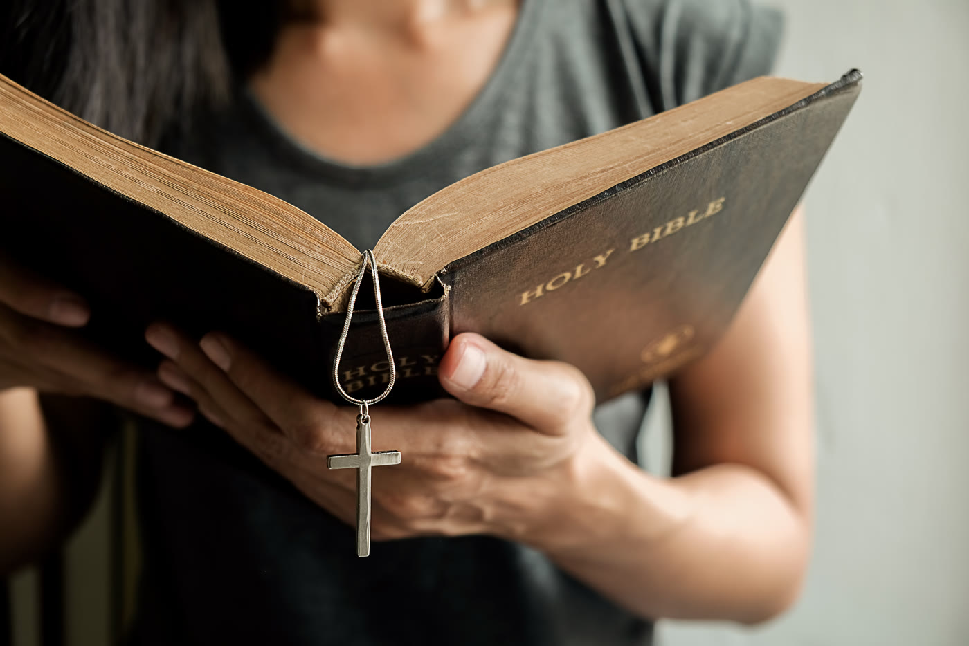 A woman holding an open Bible, with a cross